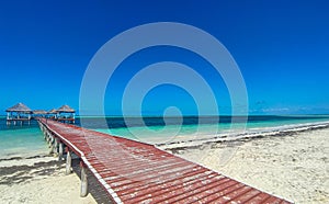 White sand beach, Atlantic Ocean with wooden pier and huts on a sunny day. Tropical seascape photography in horizontal