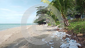 white sand beach with blue water and sky with plasic pollution