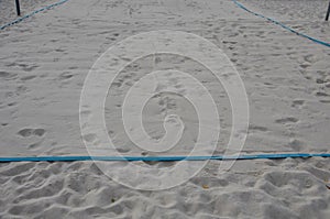 White sand beach volleyball court. white soft dunes fenced with nets. The lines of the playing field are made of blue textile plas
