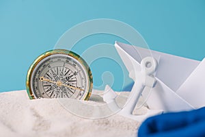 White sand with paper boat, anchor and compass