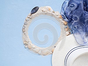 White sand and shells, hat, handkerchief on a blue background. Concept of rest on the sea