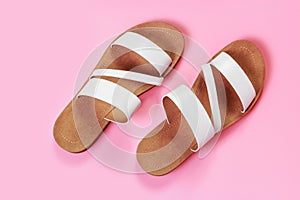 The white sandals on pink background close-up, top view.