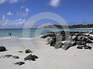 White sandy beach with scattering of rocks in forefront