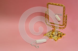 White sanitary tampon and a mirror on a pink background. Menstrual mothly cycle, means of protection. flat lay, copy space for