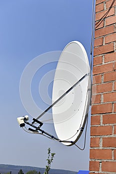 White satellite dish on blue sky background