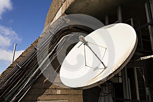 White satellite dish with wires on telecommunication tower