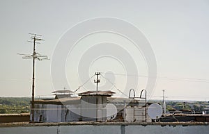 White satellite dishes with two converters mounted on residental building rooftop concrete wall. Satellite television