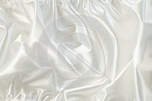 White satin or silk fabric in waves. Abstract textile background. Fabric folds