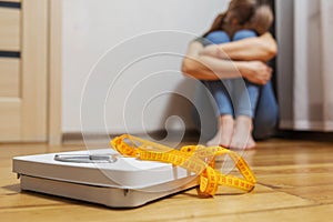 White scale and depression, upset and sad woman with measuring tape on wooden floor