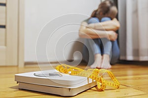 White scale and depression, upset and sad woman with measuring tape on wooden floor