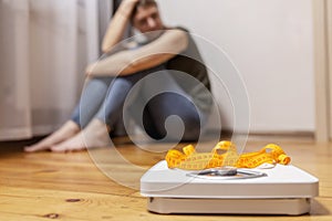 White scale and depression, upset and sad woman with measuring tape on wooden floor