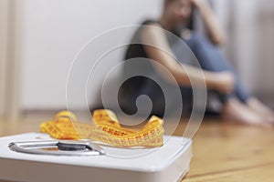 White scale and depression, upset and sad woman with measuring tape on wooden floor