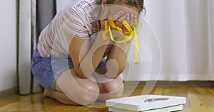 White scale and depression, upset and sad woman with measuring tape on wooden floor