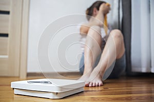 White scale and depression, upset and sad woman with measuring tape on wooden floor