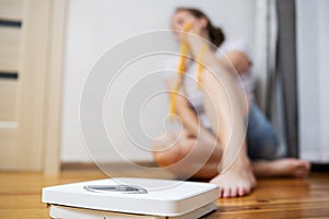 White scale and depression, upset and sad woman with measuring tape on wooden floor