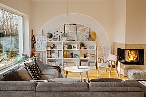 White Scandinavian living room interior with fireplace, posters, corner couch and kids toys