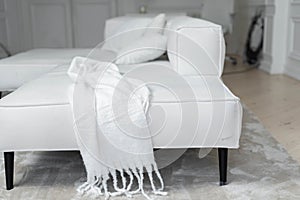 A white scarf with fringe on a white sofa