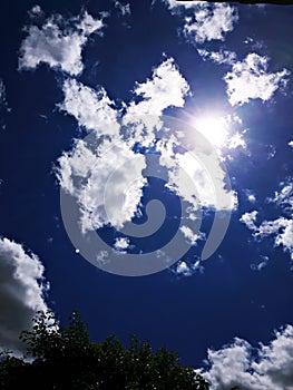 White scattered clouds in blue sky and bright white sun and the moon afar