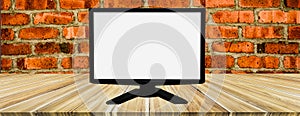 White screen computer on wooden table,brick wall background,empty space for text and image,use advertising media,montage to