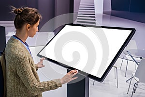 Woman using interactive empty white touchscreen display kiosk at exhibition