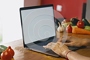 White screen. A young girl in the kitchen with a laptop is looking for a recipe. Food blogger concept.