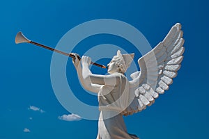 White sculpture of an angel holding trumpet on the tropical island.