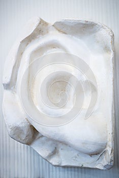 White sculpture of the human ear from gypsum. Vertical frame