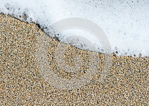 White sea foam on a yellow brown sand grains