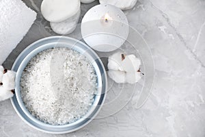 White sea salt and supplies for spa scrubbing procedure on grey marble table
