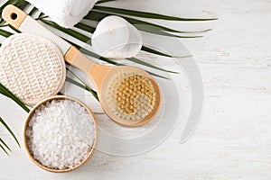 White sea salt and supplies for spa scrubbing procedure on wooden table