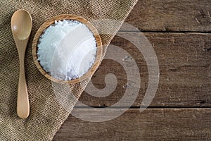 White sea salt in wood bowl with wood spoon on gunny sack cloth on brown wooden table