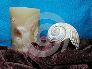 White sea shell and candle on folded scarf