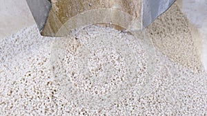 White secondary processing plastic granule comes out of the granulator crusher into small granules. Concept of plastic recycling,