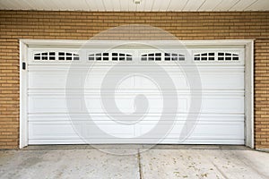 White sectional garage door with window panels and concrete driveway