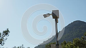 white security camera on pole in park or private area of large estate and provides round-the-clock monitoring. video