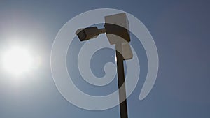 white security camera on pole in park or private area of large estate and provides round-the-clock monitoring. video