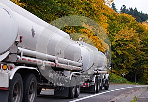 White semi truck with tank trailers on autumn trees road