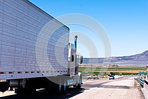 White semi truck and trailer with reflection on the road