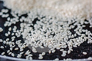 White sesame seeds over the black metal tray.