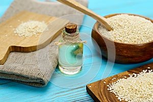White sesame seeds in a wooden bowl on dark table, Sesame oil in jar and seeds concept, Selective focus.