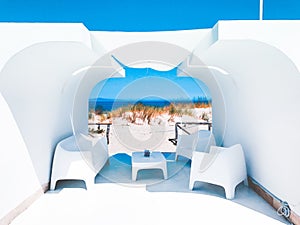 A white setting with a table and chairs and the breathtaking view of the beach in the background