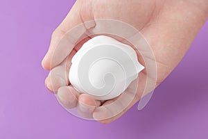 White shaving foam in the hand of a teenager on a blue bright background