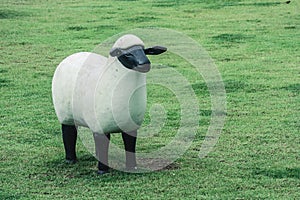 White sheep sculpture standing on green grass at public park.