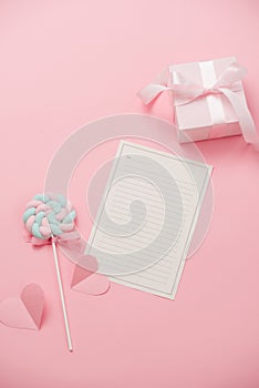A white sheet of paper for message to loved one, candy on pink background. Happy woman`s day concept. Mock up