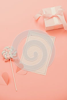 A white sheet of paper for message to loved one, candy on pink background. Happy womans day concept. Mock up