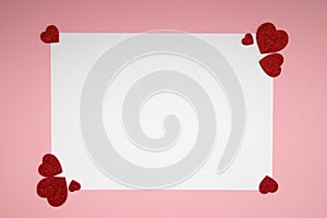 White sheet of paper for message to a loved one on a pink background with shiny hearts. Happy valentines day. Flat lay Layout.