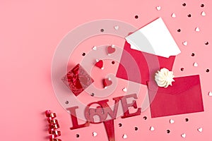 A white sheet of paper for message to loved one, red envelope, gift box, tittle sparkles,word love from black letters pen on pink