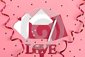 A white sheet of paper for message to loved one, red envelope, gift box, tittle sparkles,word love from black letters pen on pink