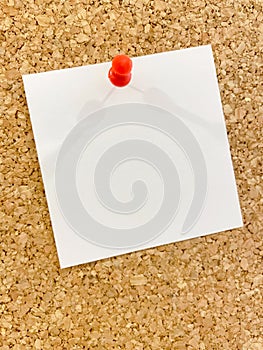 White sheet of paper pinned to a cork board with a pushpin