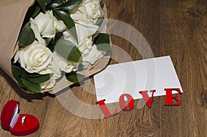 white sheet of paper on a wooden background with a bouquet of roses